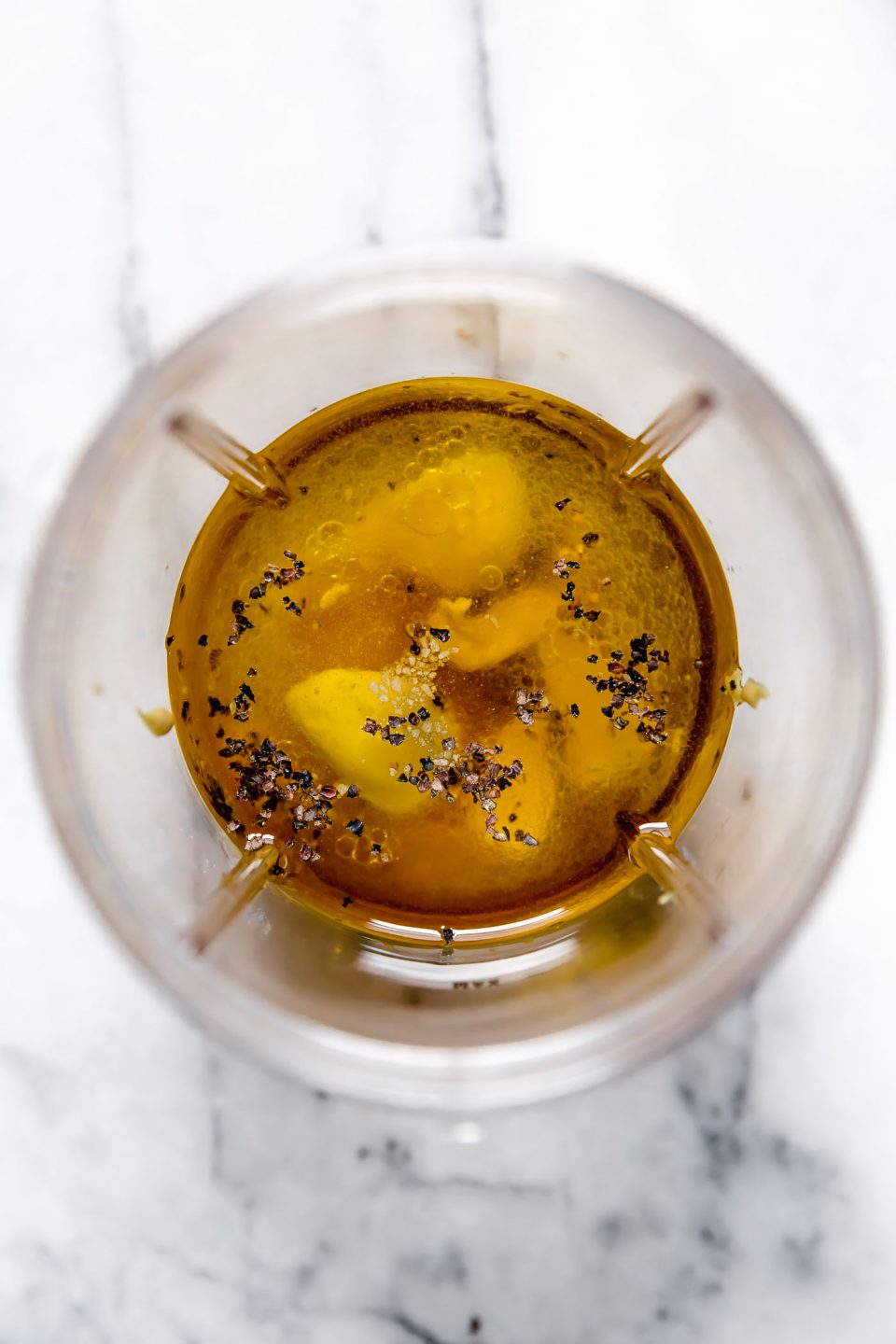 All-purpose vinaigrette ingredients (olive oil, vinegar, lemon juice, garlic, honey & Dijon mustard) in blender cup prior to blending.