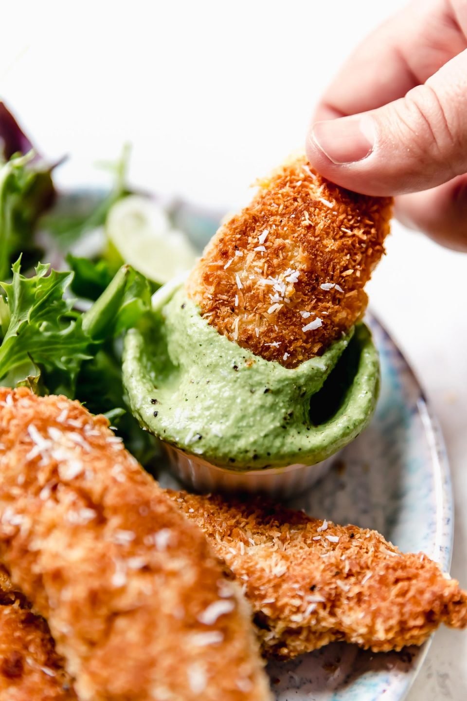 Dunking a coconut chicken tender in cilantro-lime cashew crema.