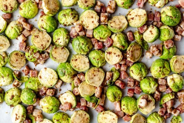 Brussels sprouts coated in Maple syrup and mustard, on a large baking sheet with dice pancetta.