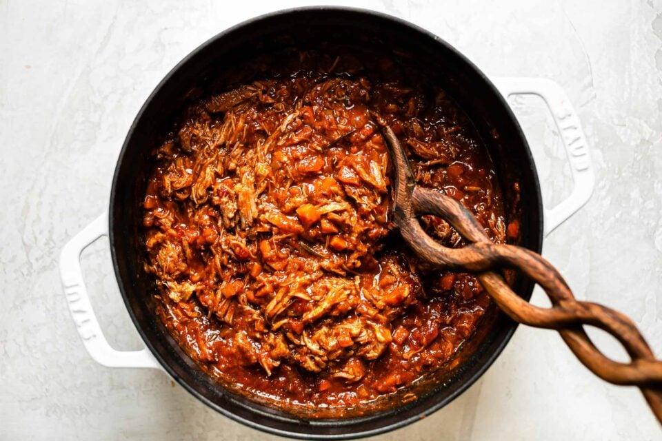 Finished pork ragu sauce inside of a large white Dutch oven.