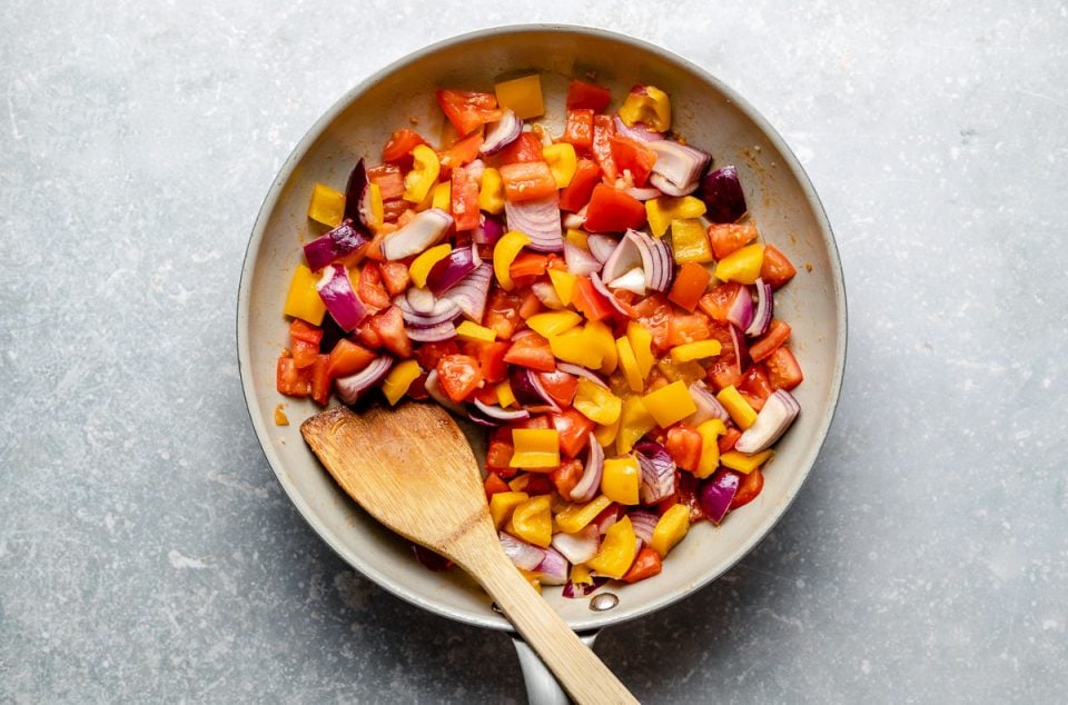 Stir fried sweet n sour veggies in a large skillet with a wooden spoon.