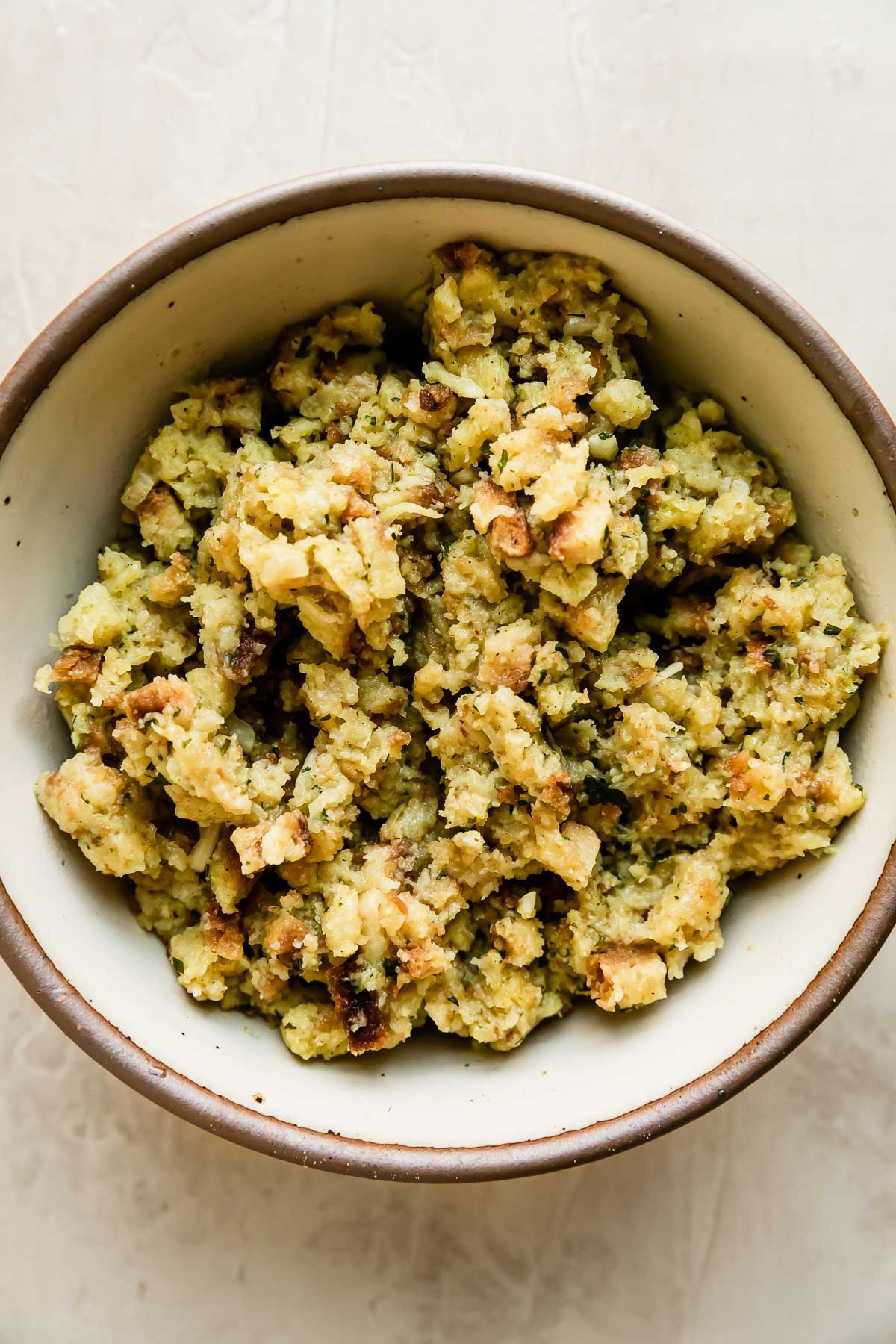 Prepared box stove top stuffing fills a large ceramic bowl that sits atop a creamy white textured surface.